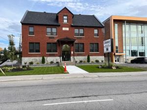 a red brick building with a black roof at Spacious 2 Bedroom Loft Apt #7 in Gatineau