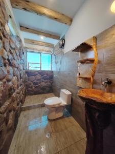 baño con aseo y pared de piedra en Villa Maru, en Calca