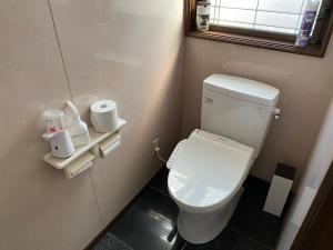 a small bathroom with a toilet and a window at ゲストハウスすまいるさん in Iba