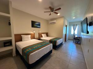 a hotel room with two beds and a ceiling fan at Oneiro Suites with Sea View in Mahahual