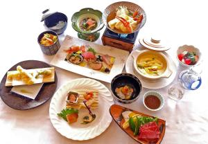 una mesa con platos de comida y tazones de comida en Yunohama Hotel, en Hakodate