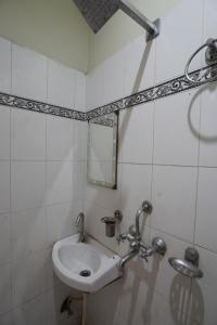 ein weißes Badezimmer mit einem Waschbecken und einem Spiegel in der Unterkunft hotel banaras darbar in Kakarmatha