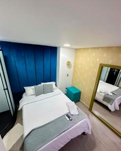 1 dormitorio con 1 cama grande y espejo en Inizio Hotel Boutique Laureles, en Medellín