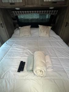 cama blanca grande con toallas y mando a distancia en Petite Manufactured unit with Large Queen Bed - 2 Tvs, en Hollywood
