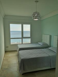 2 camas en un dormitorio con vistas al océano en AppartF3 vue panoramique sur mer, en Fnidek