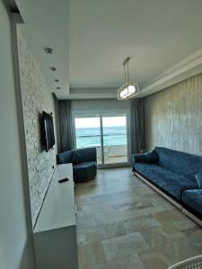 un salon avec un canapé bleu et une télévision dans l'établissement AppartF3 vue panoramique sur mer, à Fnideq