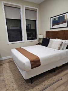 a large bed in a bedroom with two windows at Cozy Maison Apt #4 in Gatineau