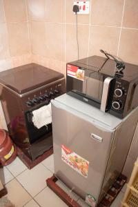 a kitchen with a stove and a refrigerator with a microwave at AriBri Apartment, Bungoma Town. in Bungoma