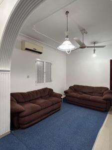 a living room with two brown couches in a room at Basil Hostel in Muscat
