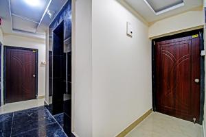 two wooden doors in a hallway with black tiles at OYO Flagship Aarvi Palace in Cuttack