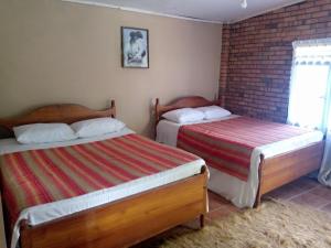 um quarto com 2 camas e uma parede de tijolos em Maliga Inn em Gampola