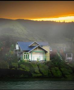 una casa en la cima de una colina con la puesta de sol en Greenlush 2, en Pīrmed