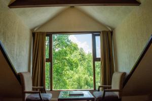 a room with a large window with two chairs and a table at The Whispering Inn Resort and Bar (An Exotic Vintage Beauty ) in Manāli
