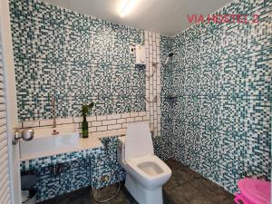 uma casa de banho com paredes em azulejos azuis e brancos e um WC. em Via Hostel Pakse em Pakse