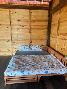 Ce lit se trouve dans un dortoir doté de murs en bois. dans l'établissement Farm cô chú Tuấn Hà, à Đà Lạt
