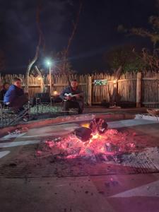 two people sitting around a fire in a yard at night at HOLLYBROOKE Campsites in Skeerpoort