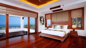 a bedroom with a large bed and large windows at Seaview Villa at Surin Beach in Thalang