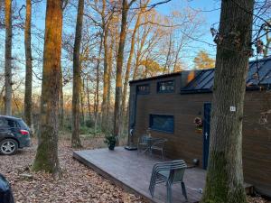 una pequeña casa en el bosque con una terraza de madera en La Tiny House de Nanou, en Rochefort