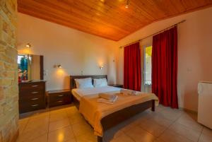 1 dormitorio con 1 cama con cortinas rojas en Ellas Hotel, en Skala Potamias