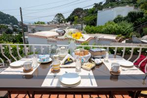 a table with plates and glasses on a balcony at Casa Rubina in Capri