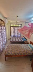 a room with a bed and a bench and curtains at Tony's Garden House Back Packers inn in Jaffna