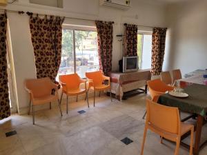 a living room with orange chairs and a television at Hotel Lakeside in Khajurāho