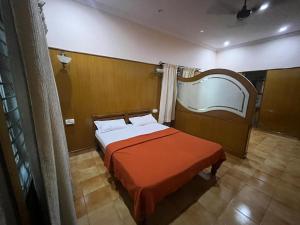 a bedroom with a bed with an orange blanket at Varal Mane in Bangalore