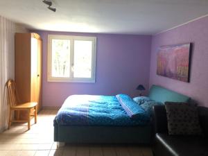 1 dormitorio con paredes moradas, 1 cama y ventana en Domaine Bellevie BnB, en Vex