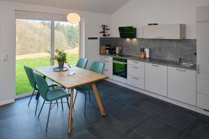 Kirschweiler的住宿－Traumweiler Ferienhäuser am Waldrand，厨房配有木桌和蓝色椅子