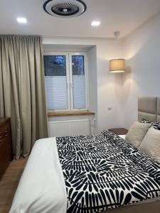 Schlafzimmer mit einem schwarzen und weißen Bett und einem Fenster in der Unterkunft 4 Seasons I in Stronie Śląskie