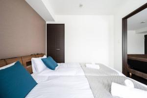 a bedroom with a large white bed with blue pillows at Shizuk +O Stay 2 in Kita-sanjō