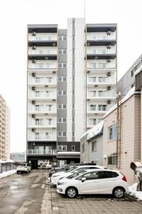 a parking lot with cars parked in front of a building at Shizuk +O Stay 2 in Kita-sanjō