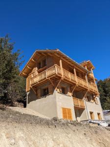 uma grande casa de madeira no topo de uma colina em chalet panoramique em Ceillac