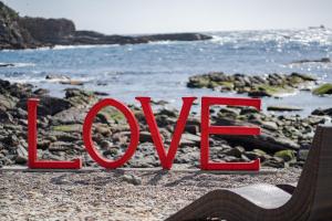 a red sign that reads love on a rocky beach at XYZ Private Spa and Seaside Resort in Shirahama
