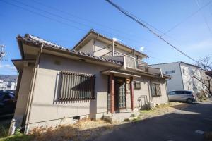 Koyanagichō的住宿－１組限定　家族連れ歓迎　松本城徒歩15分　無料駐車場2台有，一间位于街道上的白色小房子,设有阳台