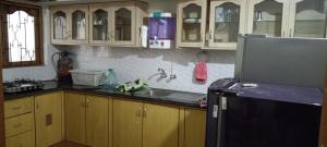 a kitchen with wooden cabinets and a black refrigerator at Suburbs Holiday Home in Dabolim +6 photos