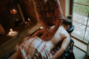 Eine Frau gibt einem Mann eine Rückenmassage in der Unterkunft Ajurweda na Jurze Agroturystyka 