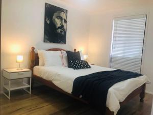 a bedroom with a bed with a portrait of a man at Penrith Relaxing Beauty 3BR Entire House Sleep 8 in Penrith