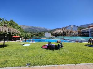 un campo de hierba con una piscina al fondo en Apartamento Martina, en Jarandilla de la Vera