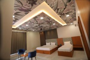 a room with two beds and a ceiling with flowers at Hotel Pride Of Chittor in Chittaurgarh