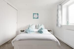 - une chambre blanche avec un lit et des oreillers bleus dans l'établissement Bed and breakfast near Truro and the A30, à Truro