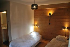 a bedroom with two beds and a wooden wall at Chalet le Réconfort, accès skis aux pieds in Saint-François-Longchamp