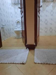 a bathroom with a toilet and two rugs in a room at Ellyz Home Stay in Moshi