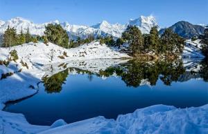 a snow covered mountain range with a reflection in a lake at Laxmi Homes in Sari