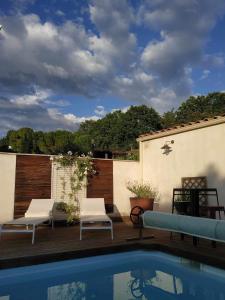 un patio avec deux chaises et une piscine dans l'établissement Chambre studio indépendante au calme vue sur piscine, à Teyran
