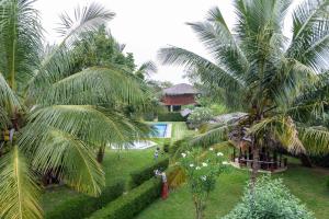 a view of a garden with palm trees and a house at The Hideout Sigiriya in Sigiriya