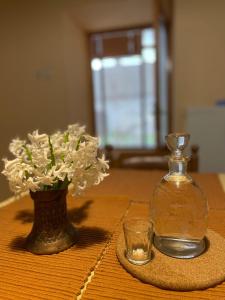 una botella de cristal y un jarrón con flores en una mesa en Kuća na selu “ANNA”, en Feketić