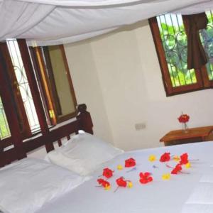 Un dormitorio con una cama con flores rojas. en Beach hote, en Tanga