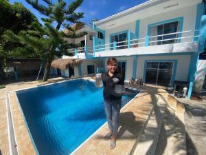a woman standing next to a swimming pool in front of a house at 囍潜Side Effects Dive Resort Dauin in Dauin