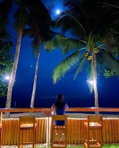 a woman sitting on a chair looking at the ocean at night at 囍潜Side Effects Dive Resort Dauin in Dauin
